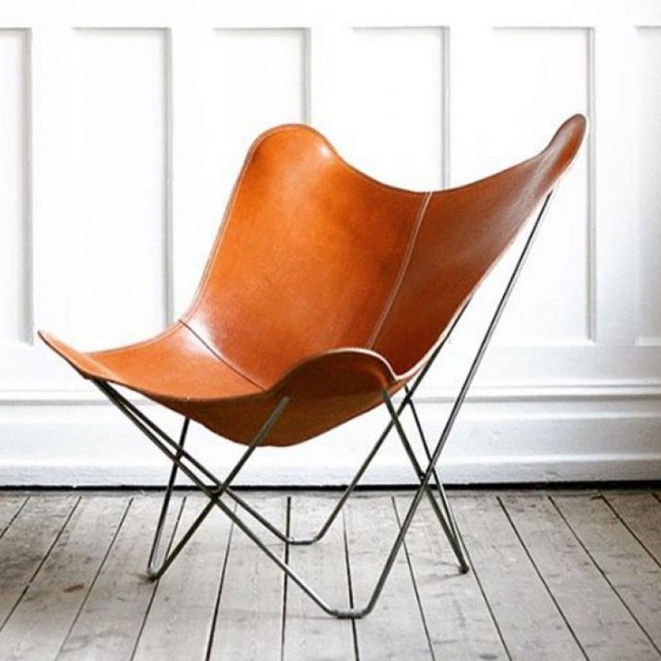 a brown chair sitting on top of a hard wood floor next to a white wall