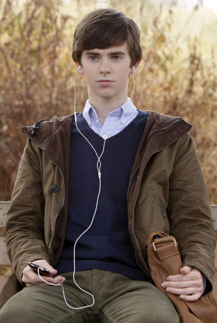 a young man sitting on a bench listening to music with earphones in his ears