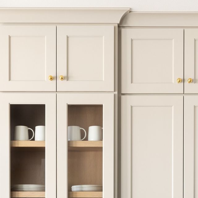 the kitchen cabinets are white with gold handles and knobs on each side, along with plates and cups