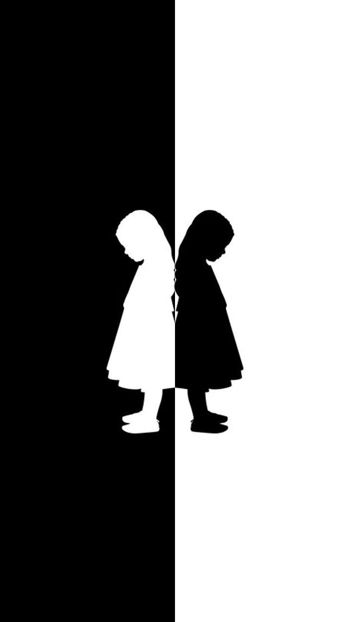 two children are standing in front of a black and white background, one is holding an umbrella