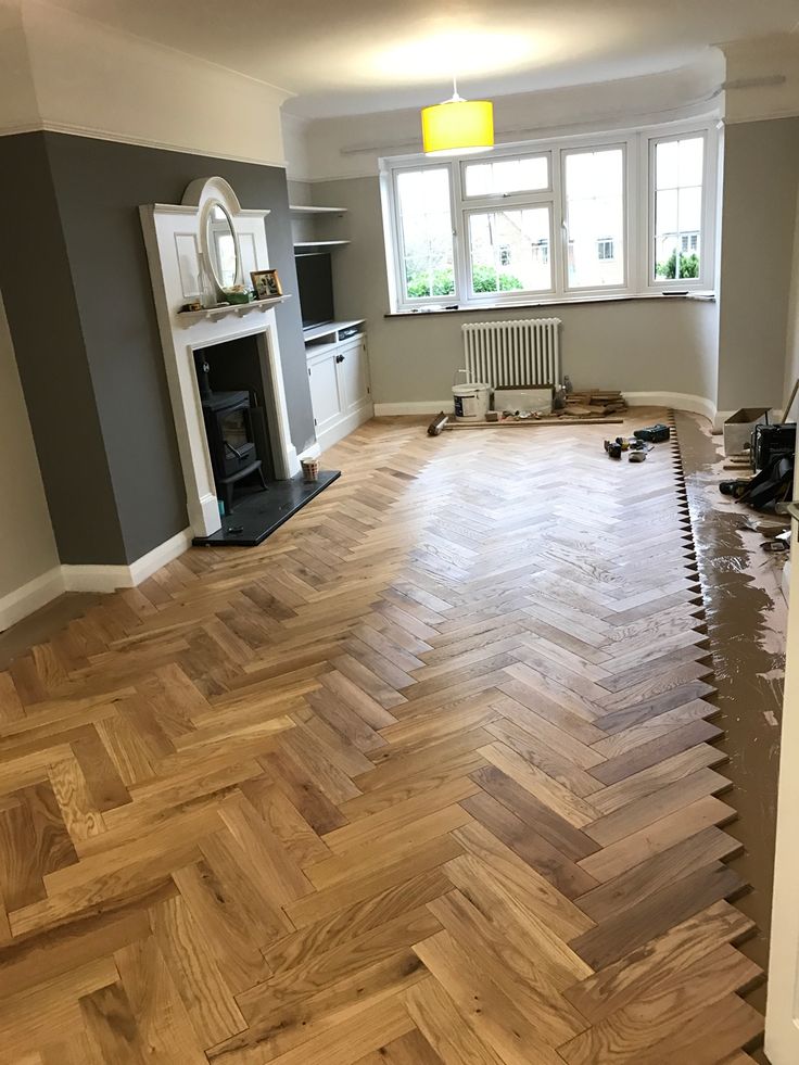 an empty room with hard wood flooring and a fire place in the corner on the far wall