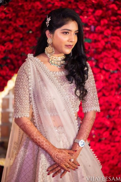 a woman in a white sari standing next to a red wall with flowers on it