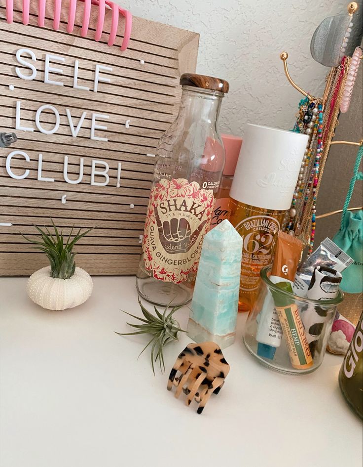 a table topped with lots of different types of personal care items next to a sign that says self love club