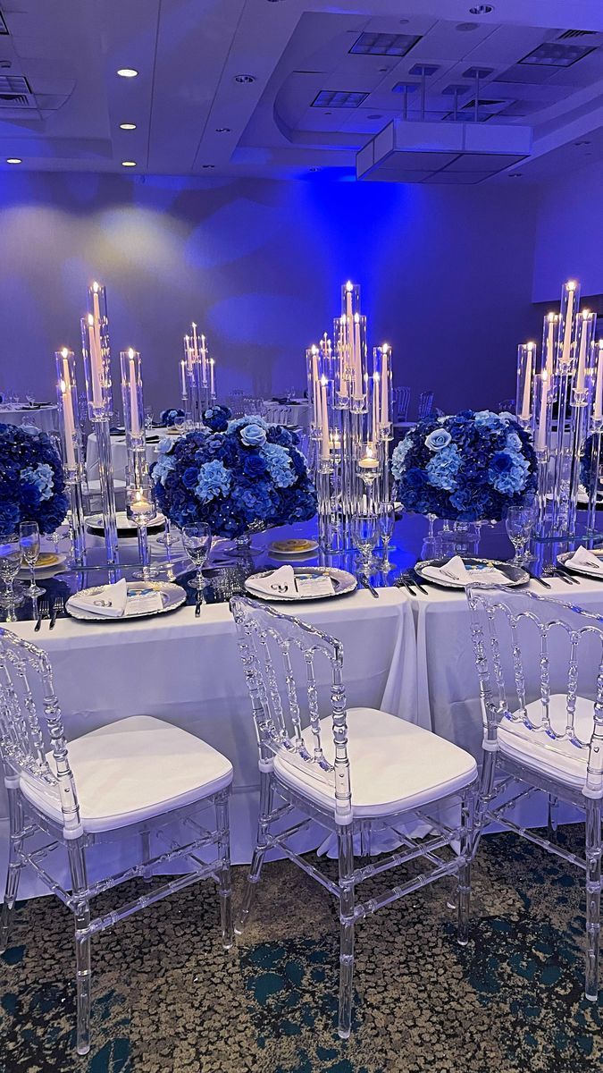 there are many chairs and tables set up for a formal function with blue flowers on them