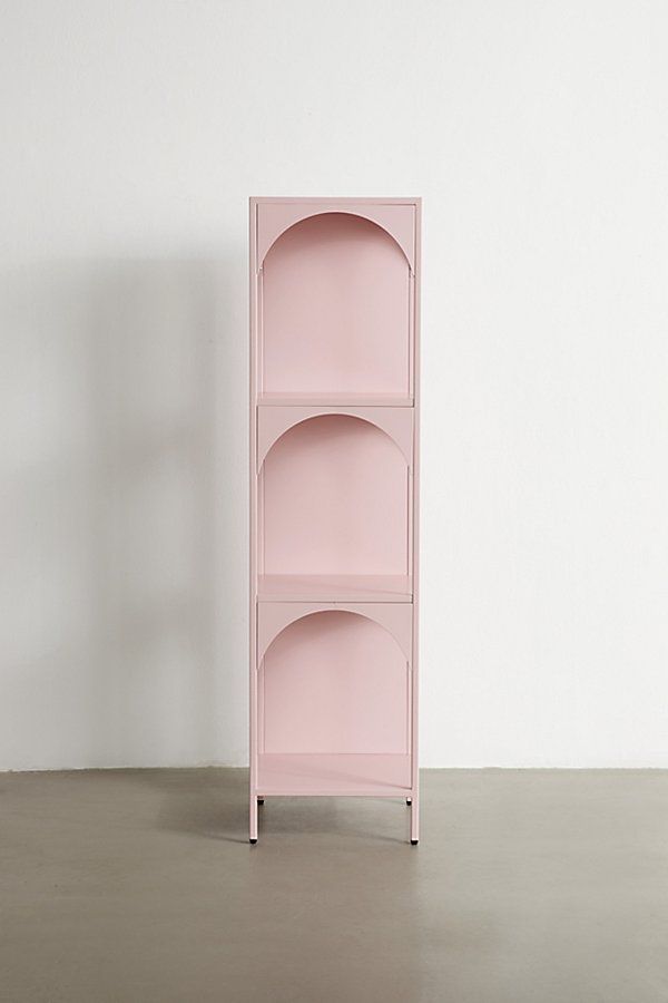 a pink shelf sitting on top of a floor next to a white wall