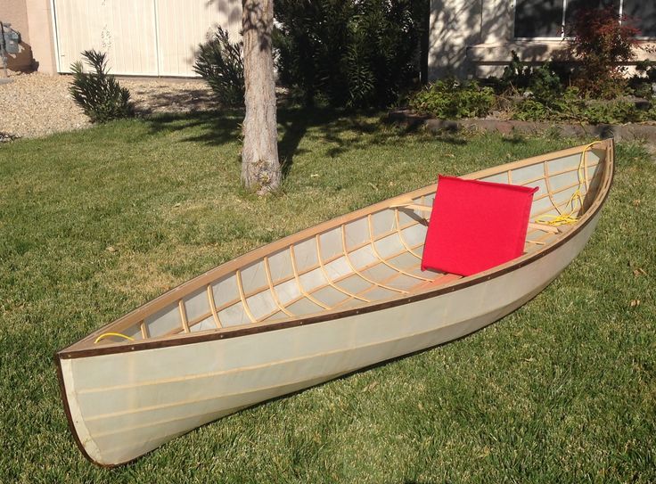 a canoe sitting on the grass in front of a house with a red box attached to it