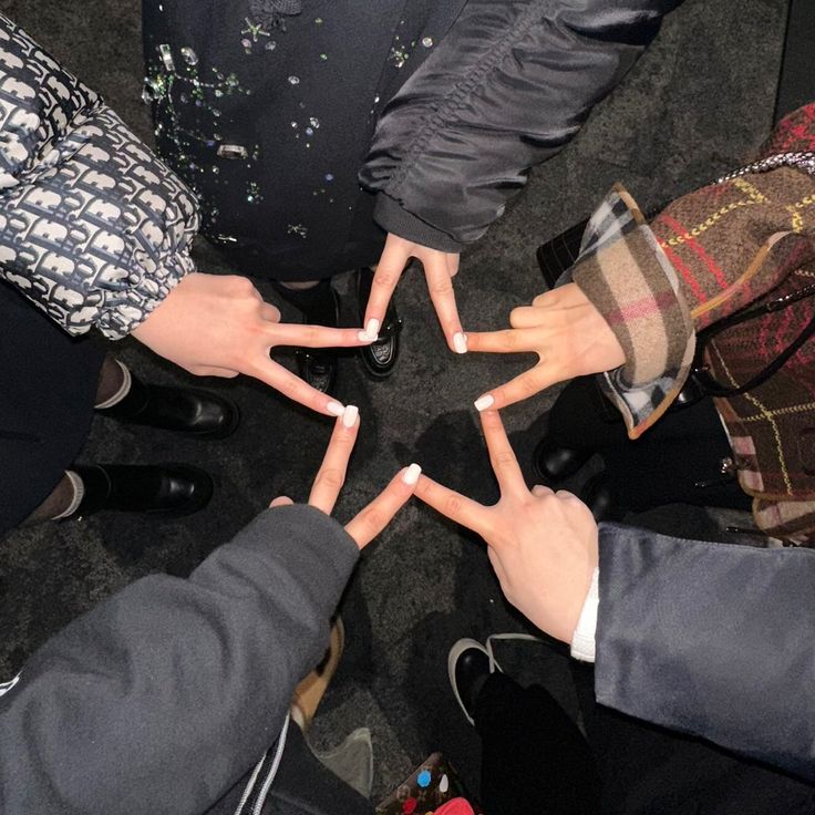 several people are standing in a circle holding their hands together and making a star shape