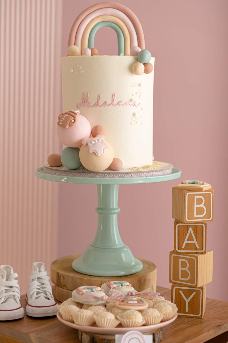 a baby shower cake and cupcakes are displayed on a table with pink walls