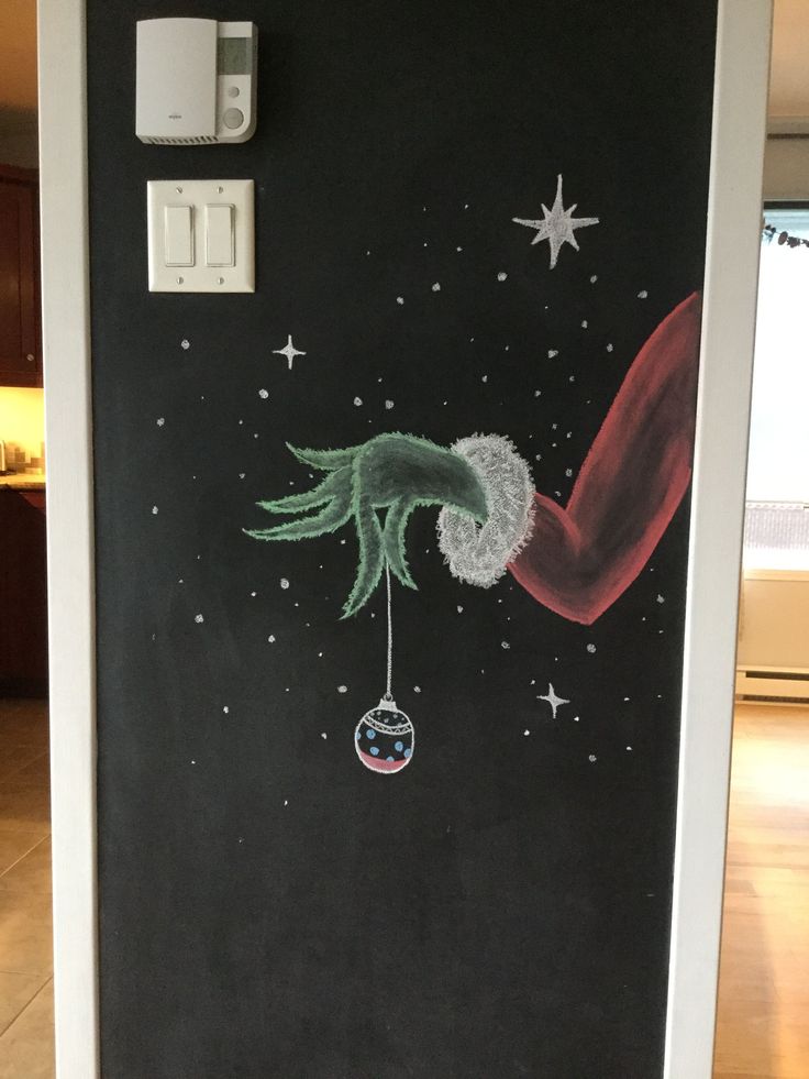 a chalkboard drawing of a christmas tree hanging from a light switch on a black wall