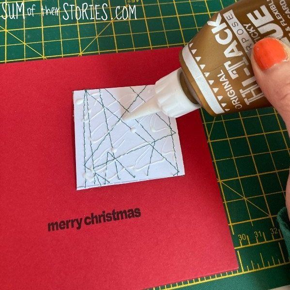 someone is making a christmas card with glue