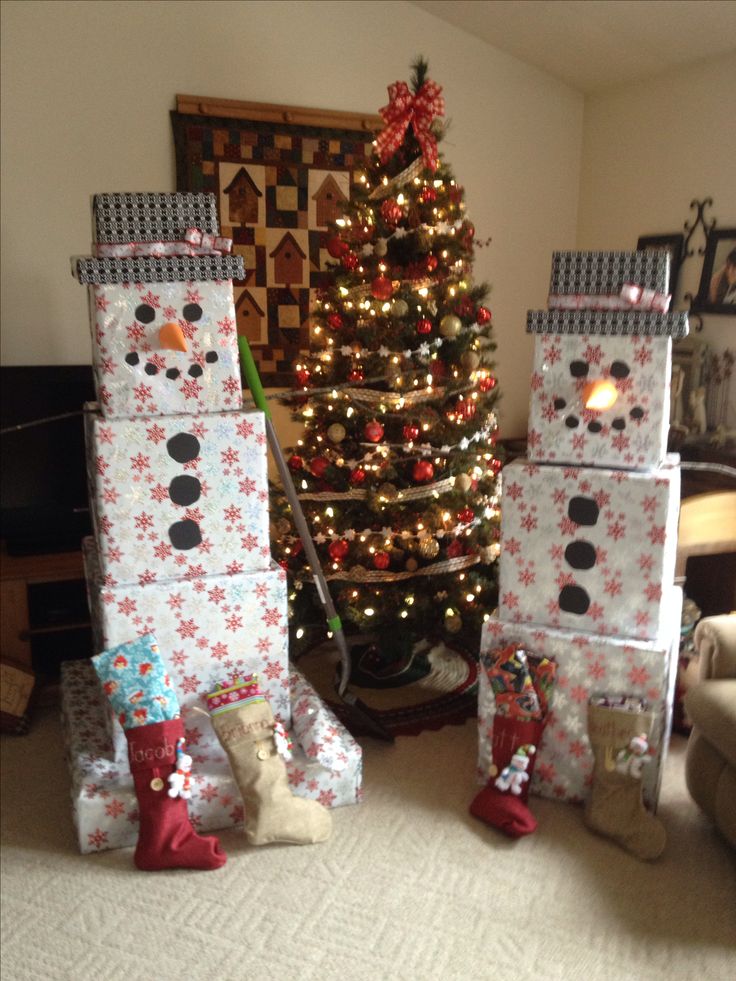 two snowmen made out of boxes next to a christmas tree