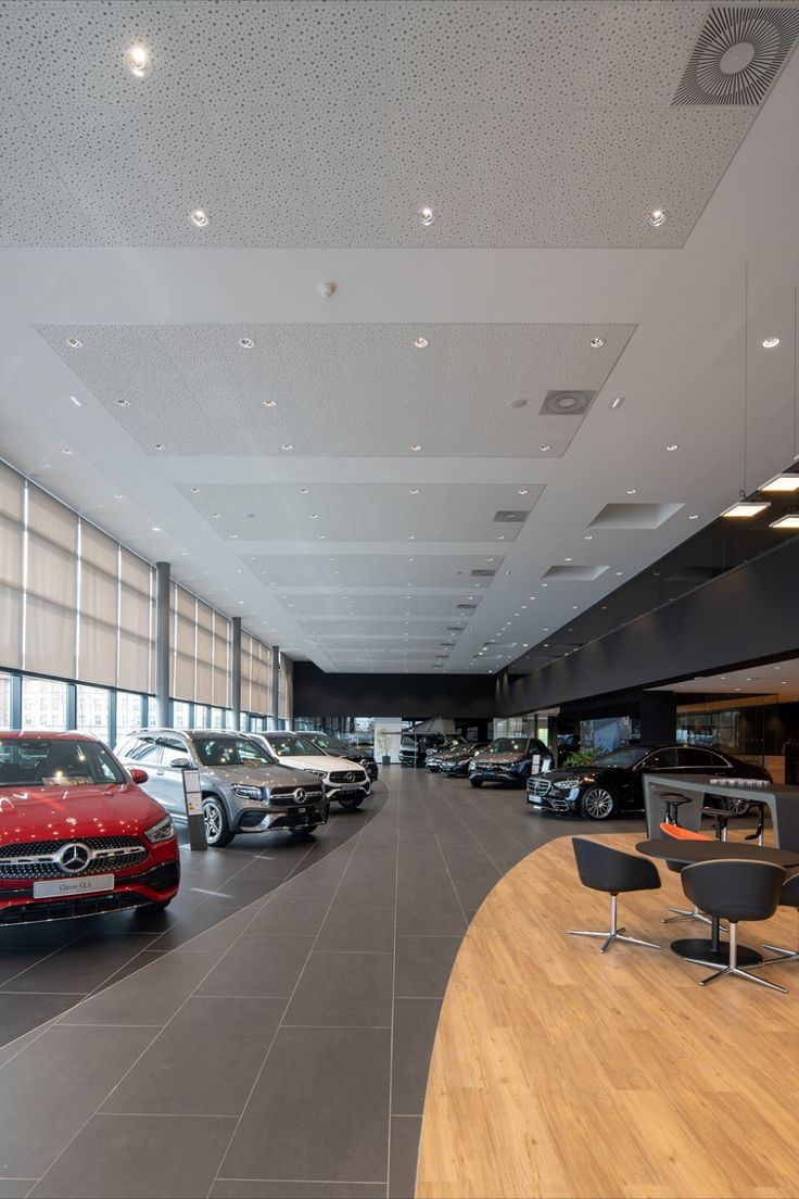 a car showroom filled with lots of different types of cars parked in front of large windows