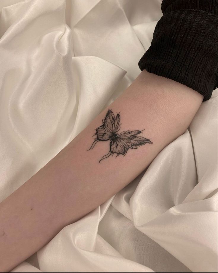 a woman's arm with a small flower tattoo on the left side of her arm