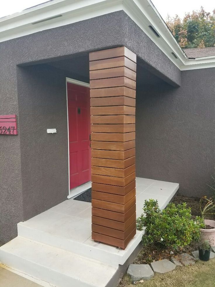 a red door is on the side of a gray house with steps leading up to it