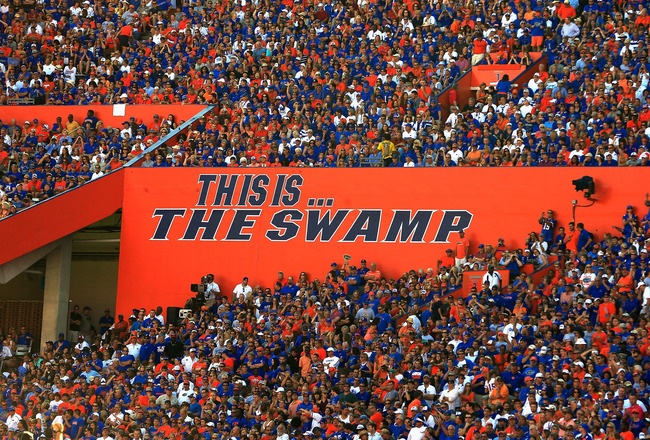 a large group of people in the stands at a football game with an orange sign that says this is the swamp