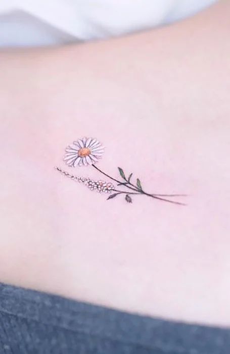 a small tattoo on the back of a woman's shoulder, with a single flower