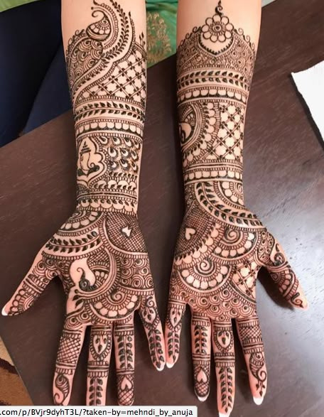 two hands with henna tattoos on them, one is showing off the intricate design