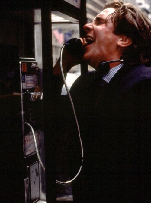 a man talking on a phone while standing in front of a payphone with his mouth open