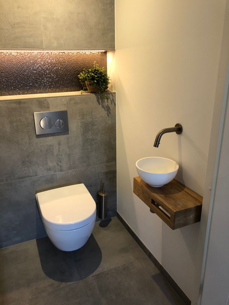 a white toilet sitting next to a bathroom sink under a faucet mounted on a wall