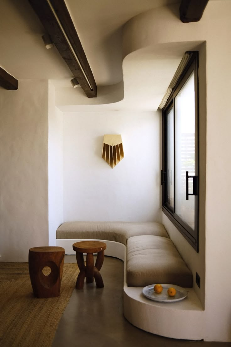 a room with white walls and wooden furniture on the floor next to a large window