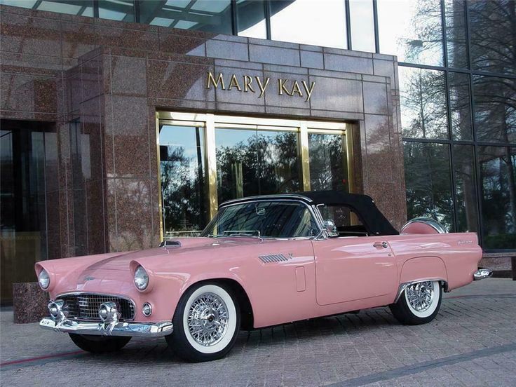 an old pink car is parked in front of the mary kay building, where it's located