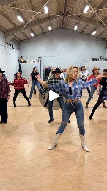 a group of people dancing in a large room with one woman holding her arms out to the side