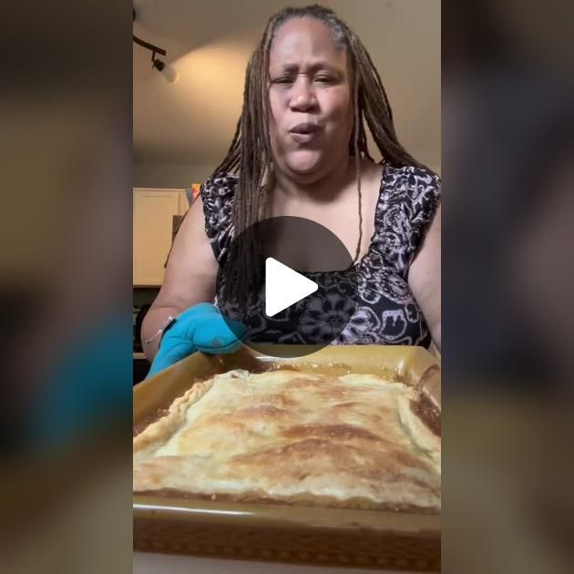 a woman with long dreadlocks making a face next to a large pan of food