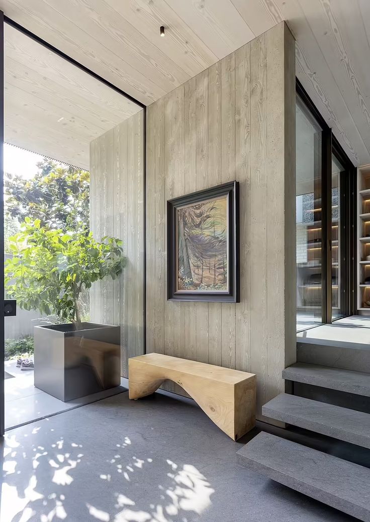 a wooden bench sitting in front of a painting on the wall next to some stairs