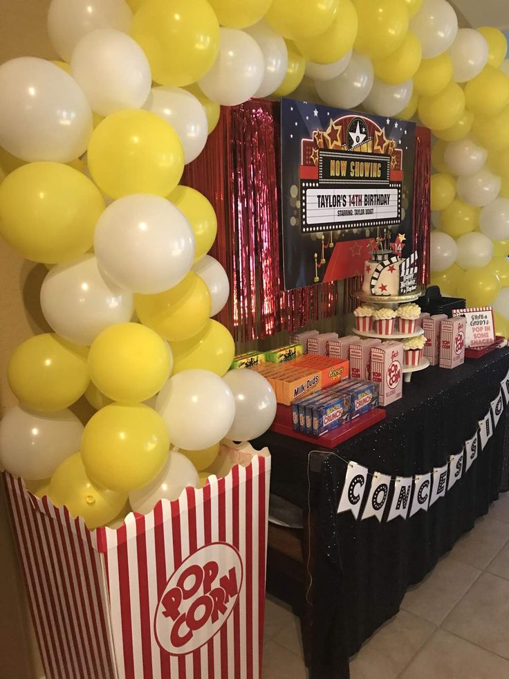 popcorn boxes and balloons are set up in front of a movie themed birthday party table