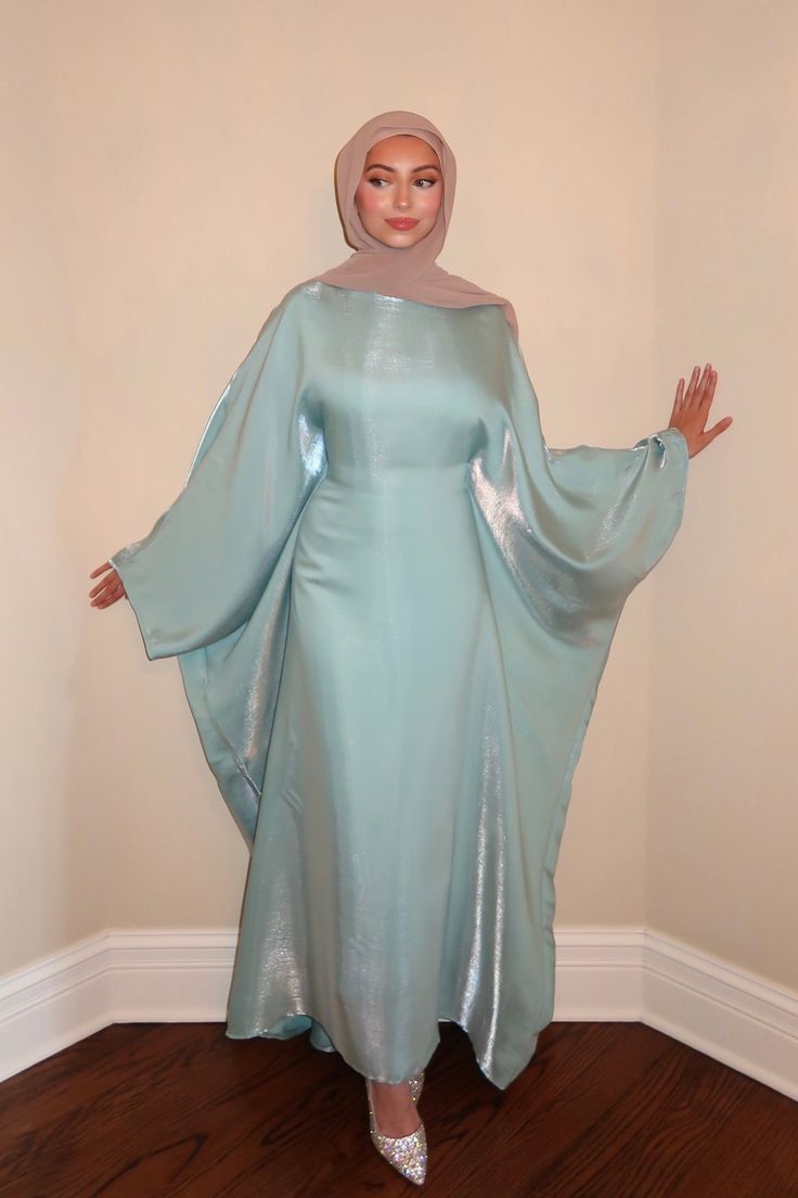 The Turquoise Butterfly Abaya is crafted from an iridescent, lightweight fabric. This piece features a hidden belt inside to create the signature butterfly abaya effect. Its flowing design and delicate shimmer will make you feel effortlessly elegant and confident. ABOUT ME Iridescent, turquoise blue fabric Batwing long sleeves Hidden belt Length: 54” 100% Polyester Made in USA Ethically made CARE Hand Wash Separately Cold No Bleach Line Dry Do Not Iron Steam If Needed Do Not Dry Clean *Follow th Butterfly Abaya Design, Cargo Outfits, Iridescent Fashion, Cultural Clothes, Butterfly Abaya, Blue Abaya, Abaya Outfit, Turquoise Butterfly, Popular Clothing Styles