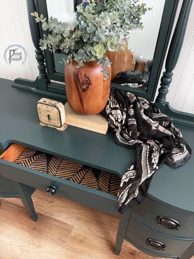 a green table with a mirror and some plants on it, next to a planter