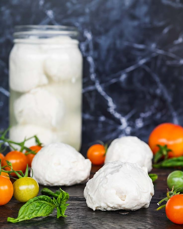 tomatoes, mozzarella and basil are on the table next to a mason jar