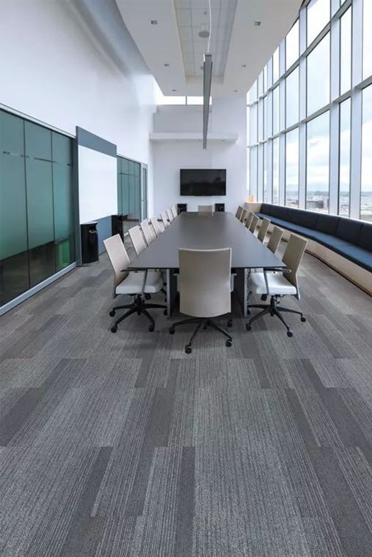 an empty conference room with large windows overlooking the cityscape, and several chairs around a long table