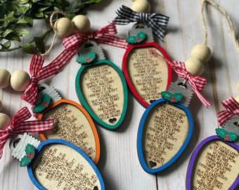 four wooden ornaments with words on them and bows hanging from the strings next to some greenery