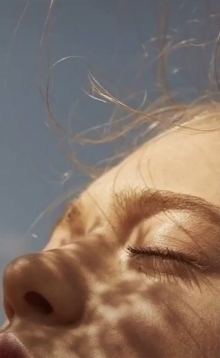 a close up of a person's face with their eyes closed and hair blowing in the wind