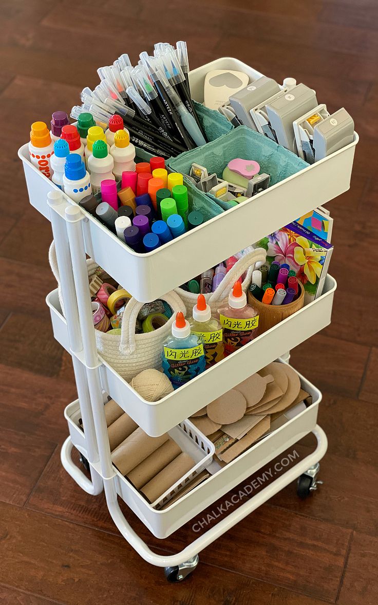 a white cart filled with craft supplies on top of a wooden floor