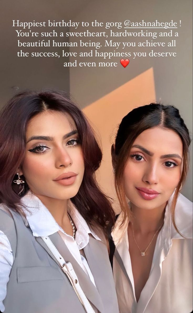 two beautiful women standing next to each other in front of a sign that says, happy birthday