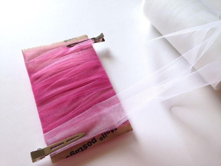 a piece of pink fabric with white netting on it and a pair of scissors next to it