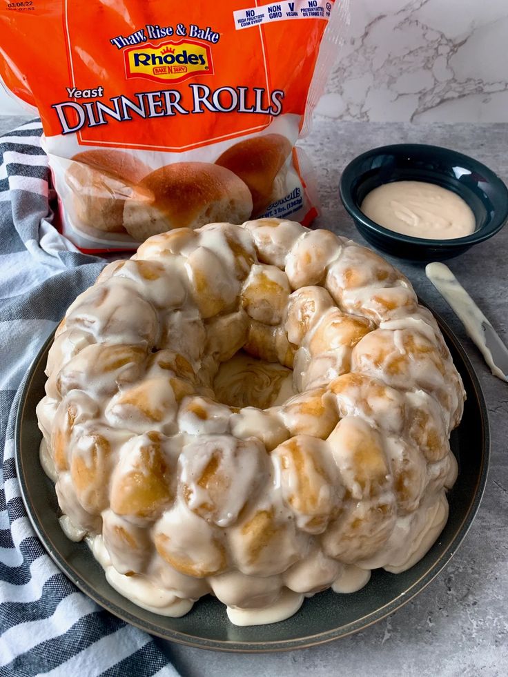 a bundt cake sitting on top of a plate next to a bag of dinner rolls