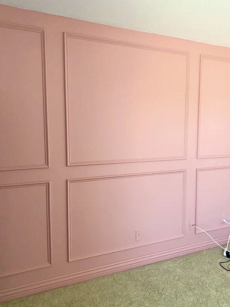 an empty room with pink walls and two laptops on the floor