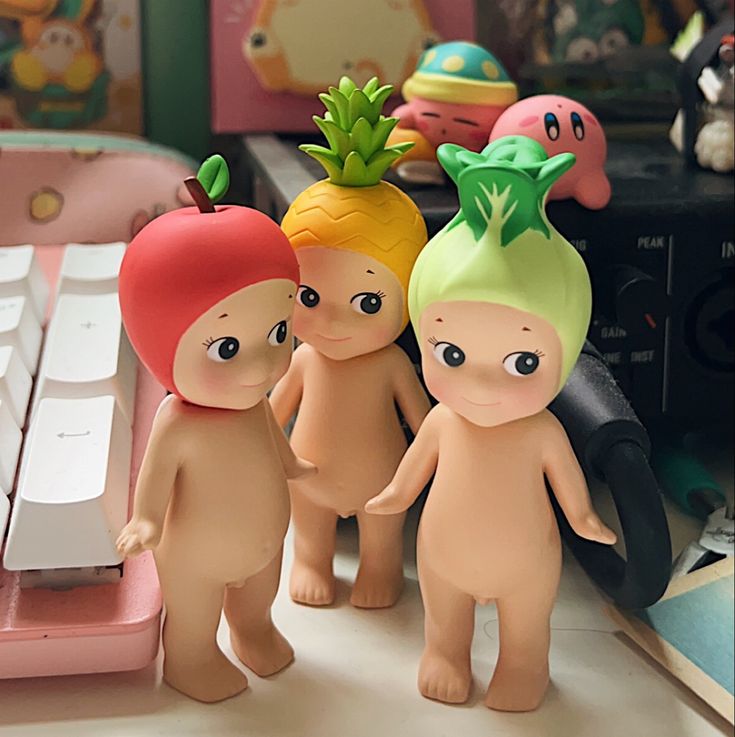 three little figurines are standing next to a computer keyboard and some other toys