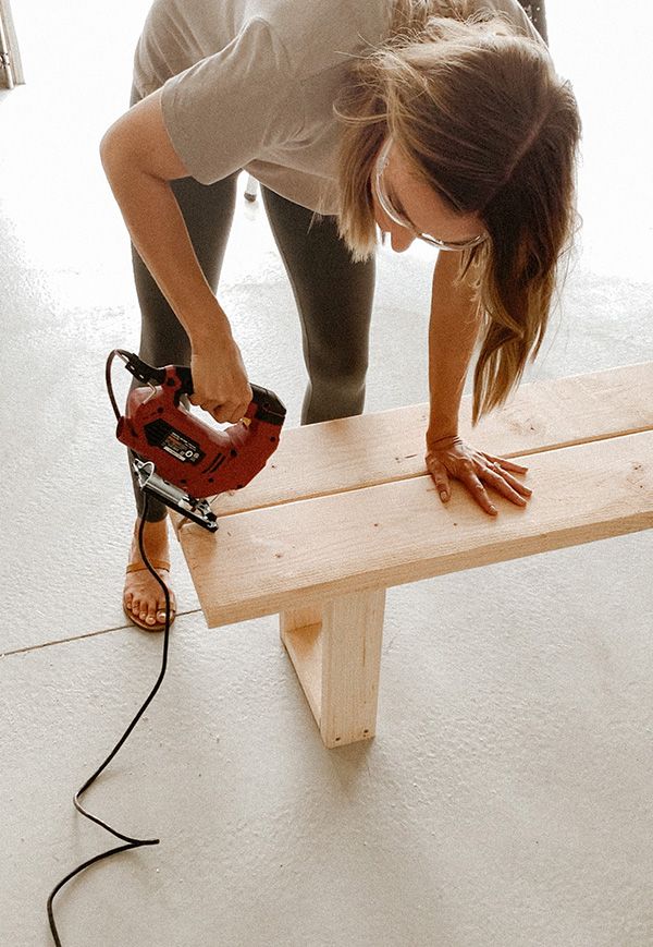 a woman is working on a bench with a power drill and a cordless saw