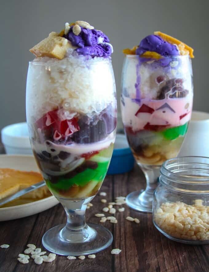 two glasses filled with desserts sitting on top of a wooden table