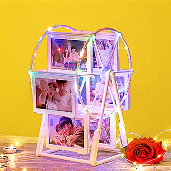 a ferris wheel with pictures on it next to some candles and flowers in front of a yellow wall