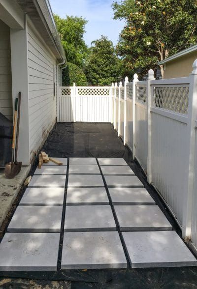 a white picket fence next to a house with a broom on the ground in front of it