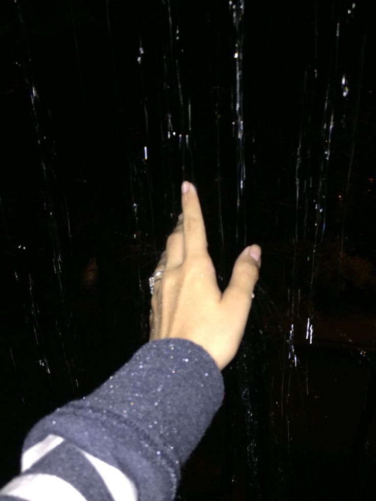 a person's hand reaching for something in the dark with water droplets on it