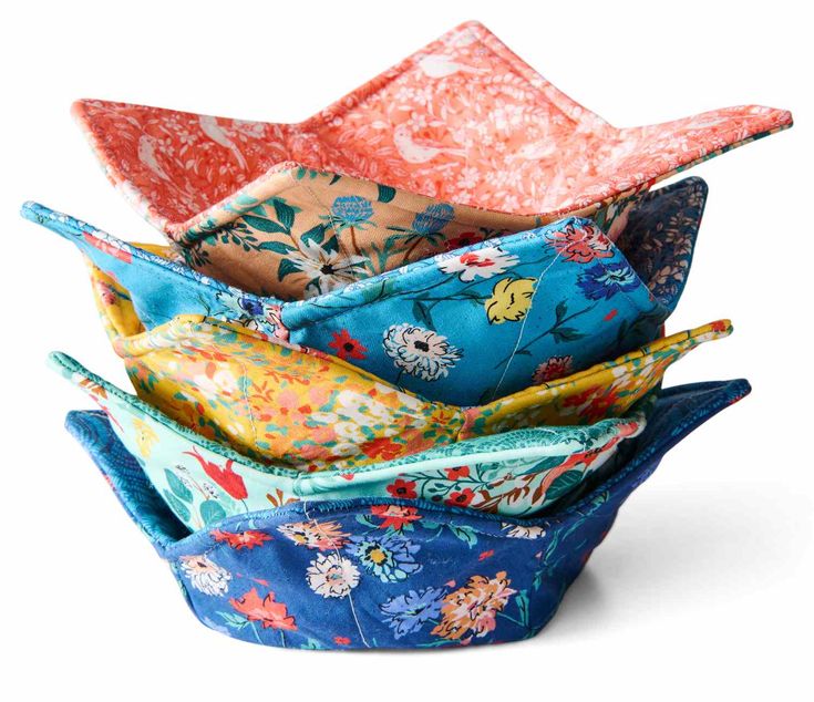 four different colored flowered fabric bowls stacked on top of each other, with one in the middle