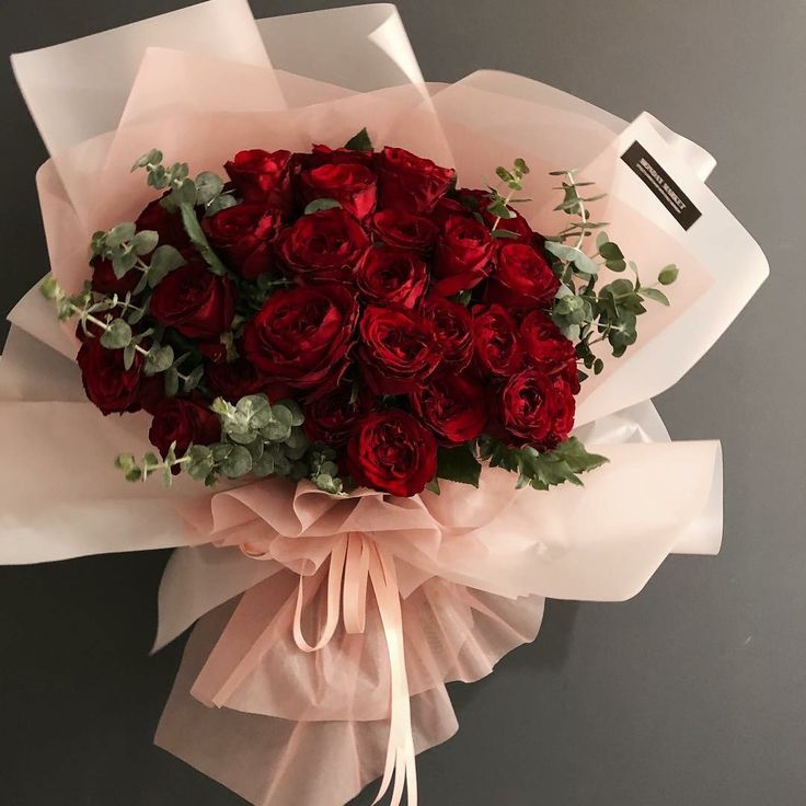 a bouquet of red roses wrapped in pink paper