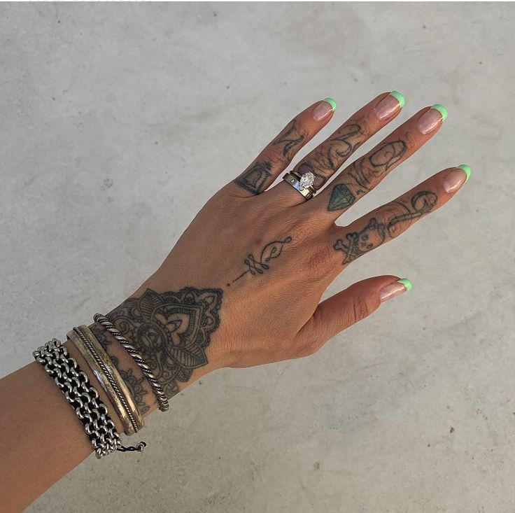 a woman's hand with tattoos and rings on it