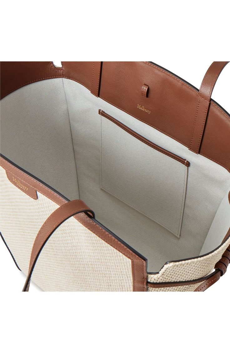 a brown and white handbag is open to show it's inside compartment,